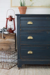 Dresser painted Midnight Blue with Homestead House Milk Paint, shown near a plant, red lantern, crate, and sneakers.