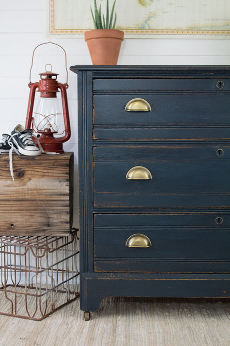 Dresser painted Midnight Blue with Homestead House Milk Paint, shown near a plant, red lantern, crate, and sneakers.