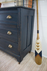 Wooden dresser with three drawers painted Homestead House Midnight Blue Milk Paint, shown on a striped rug.