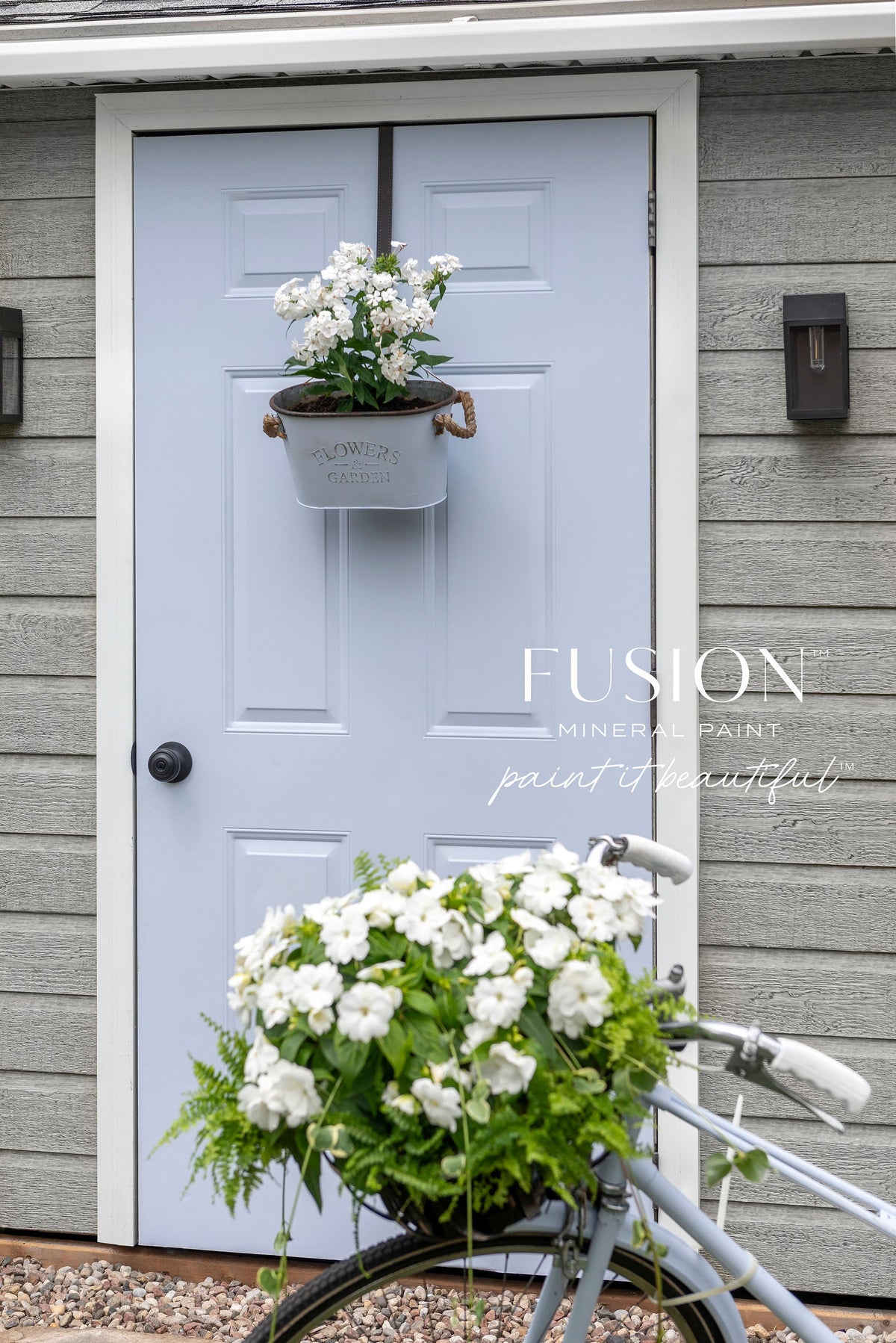 White door painted in Mist Fusion Mineral Paint, flanked by two flower pots, set against wood siding.