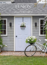 Gray shed with white door, potted flowers, and a Mist Fusion Mineral Paint bike featuring a basket of flowers.