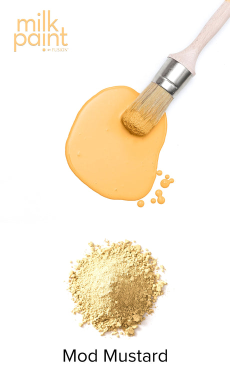 Paintbrush with Mod Mustard Milk Paint by Fusion Mineral Paint and yellow powder on white background.