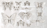 Twelve white I.O.D. Monarch Mould ornaments displayed on a textured off-white wall with a patterned border.