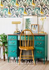Teal vintage desk finished with Homestead House Montclair Milk Paint placed in front of colorful wallpaper.