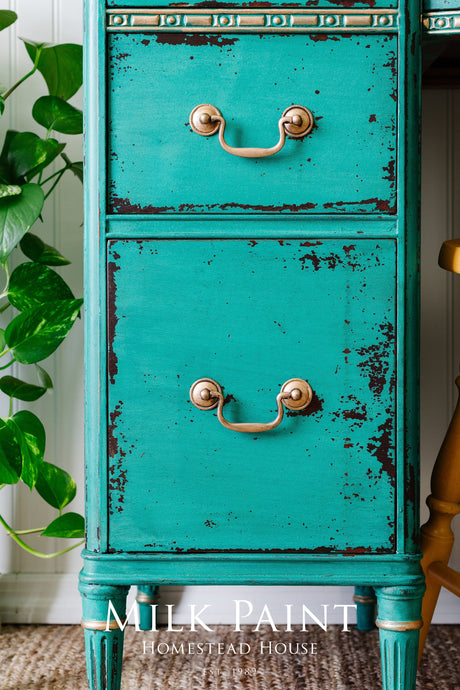 Distressed turquoise dresser with brass handles, plant to the left, Montclair Milk Paint by Homestead House text below.