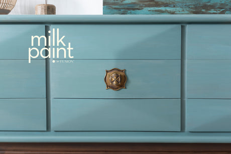 Blue dresser with brass handle; “Monterey Milk Paint by Fusion Mineral Paint” text displayed on the left.