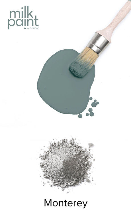 Paintbrush with greenish Monterey Milk Paint by Fusion Mineral Paint and gray powder underneath.