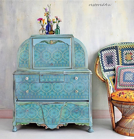 Blue vintage cabinet with Morocco Paint Inlay by IOD, Iron Orchid Designs, next to a wicker chair with crochet cushions.
