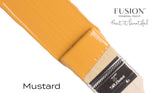 Paintbrush dipped in Mustard Fusion Mineral Paint, all-in-one acrylic by Fusion Mineral Paint.