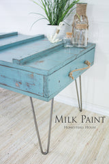 Blue wooden table in Niagara Green Milk Paint by Homestead House with metal legs on a woven rug.