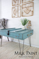 Blue wooden table with hairpin legs, plant, jars; Homestead House Niagara Green Milk Paint displayed at bottom.