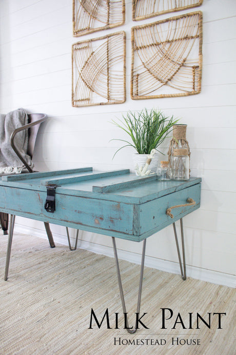 Blue wooden table with hairpin legs, plant, jars; Homestead House Niagara Green Milk Paint displayed at bottom.