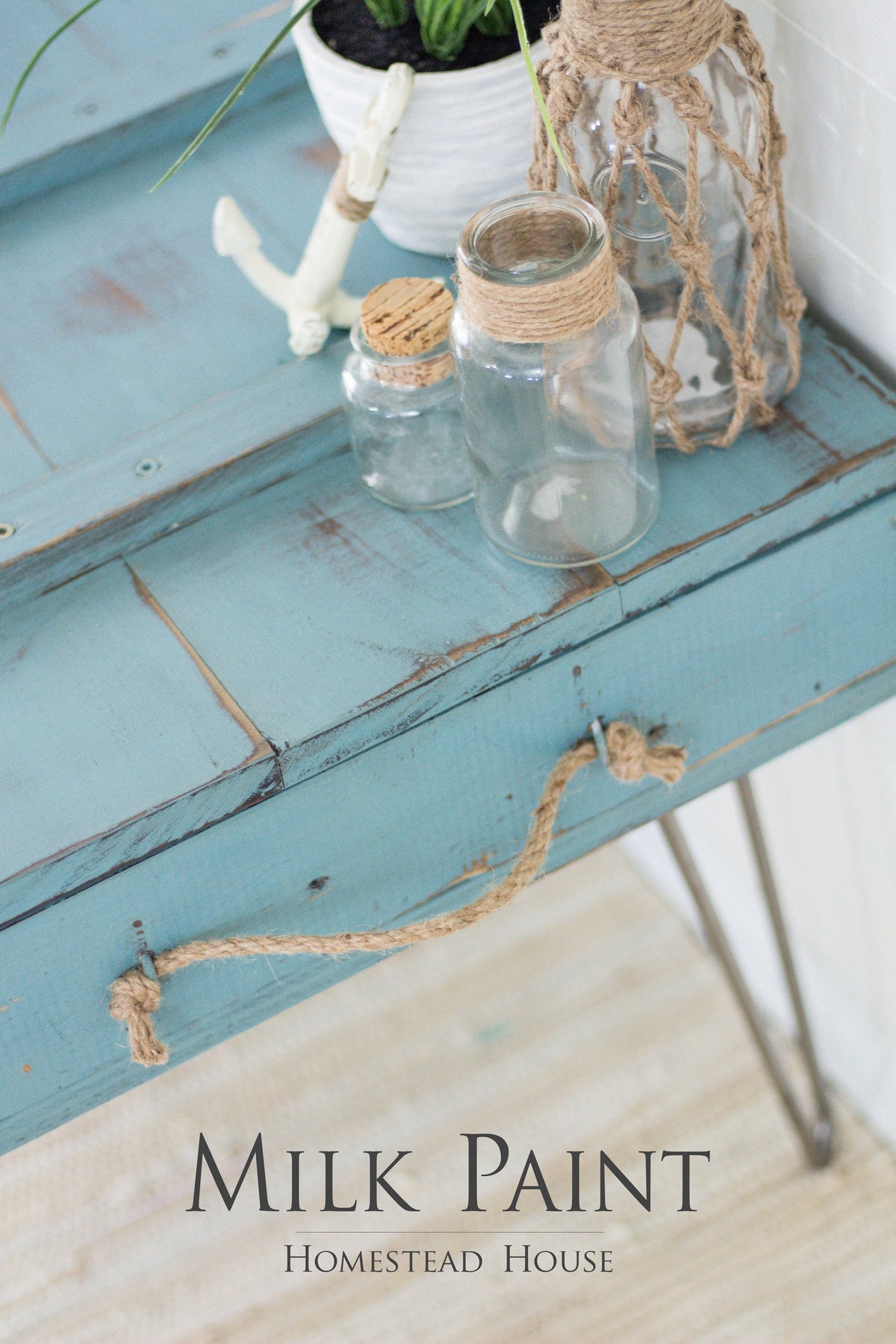 Blue wooden table with jars, rope, plant, and text: Niagara Green Milk Paint by Homestead House.