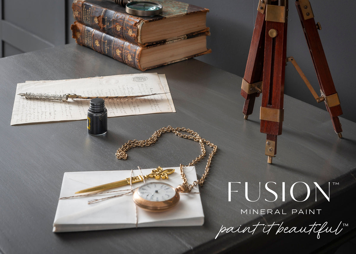 Old books and a quill on a desk, styled in Oakham with a classic matte finish, Fusion Mineral Paint text visible.