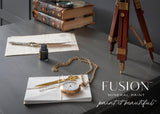 Old books and a quill on a desk, styled in Oakham with a classic matte finish, Fusion Mineral Paint text visible.