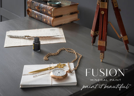Old books and a quill on a desk, styled in Oakham with a classic matte finish, Fusion Mineral Paint text visible.