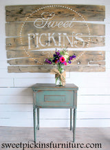 Weathered green side table in front of a rustic sign painted with Old Fashioned Milk Paint’s Ocean – Sweet Pickins.
