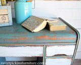 Desk finished with Old Fashioned Milk Paint in Ocean, shown with books, a metal box, and a blue pitcher on top.