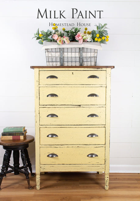 Yellow Ochre Milk Paint dresser by Homestead House next to a stool stacked with books and topped with flowers.