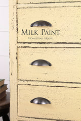 Distressed yellow dresser in Ochre Milk Paint by Homestead House, three metal handles, branded top drawer.