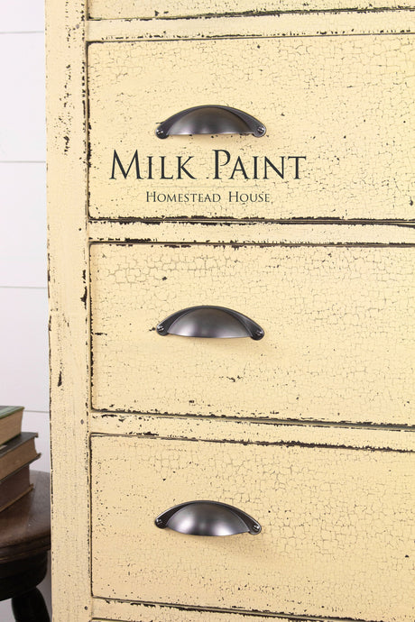 Distressed yellow dresser in Ochre Milk Paint by Homestead House, three metal handles, branded top drawer.