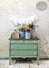 Green dresser painted in Oh Olive! by Old Fashioned Milk Paint, topped with books, flowers, and garland.
