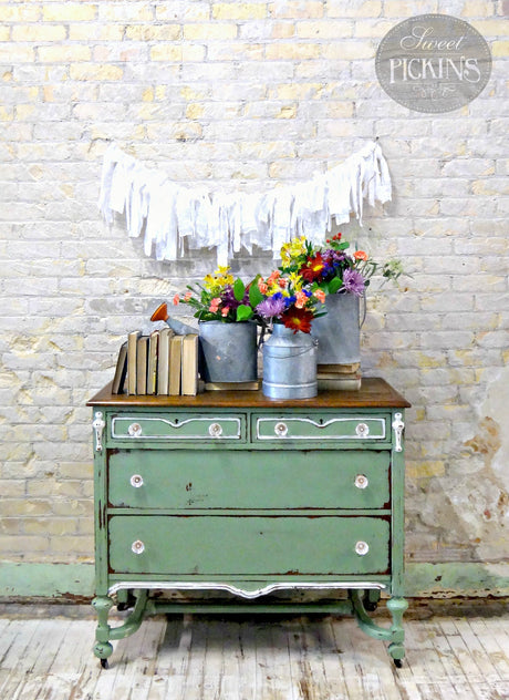 Green dresser painted in Oh Olive! by Old Fashioned Milk Paint, topped with books, flowers, and garland.
