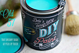 Open can of Old ’57 DIY Paint by DIY Paint Co., turquoise color, with brush and lid nearby.
