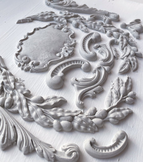 White plaster moldings crafted with the Olive Crest Mould by IOD displayed on a flat surface.