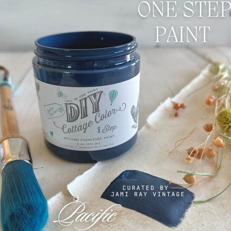 Pacific DIY Cottage Color paint by DIY Paint Co. with brush and dried flowers on white wood surface.
