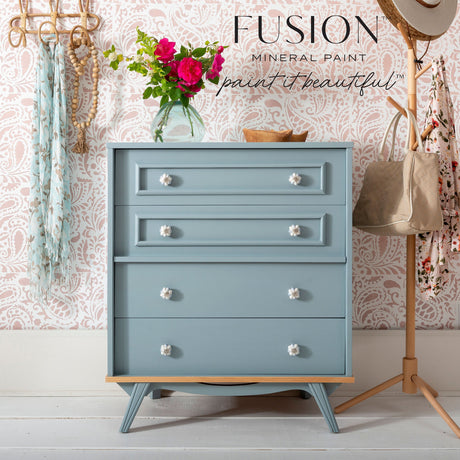 Chest in Paisley Fusion Mineral Paint with floral knobs, set against a pink patterned wall and coat rack.