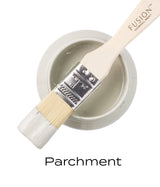 Paintbrush with white Fusion Mineral Paint rests on open jar of Parchment by Fusion Mineral Paint.