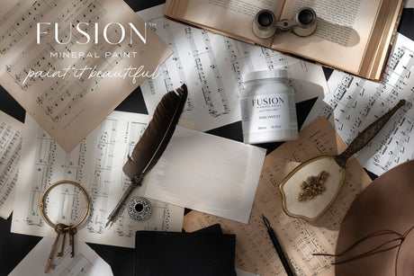 Parchment Fusion Mineral Paint by Fusion displayed on sheet music with a feather, book, and magnifier.