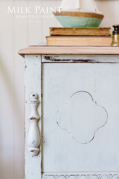 White Parlour Milk Paint cabinet by Homestead House with decorative handle, books, and decor on top.