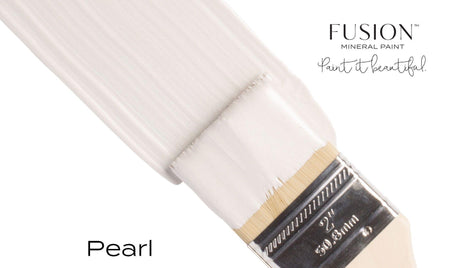Paintbrush coated with Fusion Mineral Paint Pearl Metallic, showing subtle mica shimmer in an off-white shade.