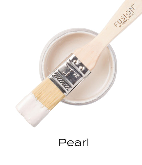 Paintbrush with white paint resting on a jar labeled “Pearl Metallic Fusion Mineral Paint” by Fusion Mineral Paint.