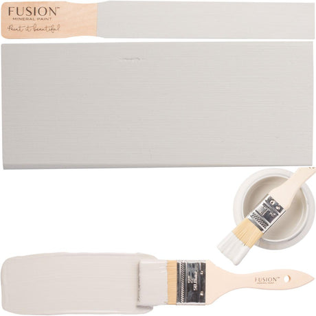 Brush, wood sample, and open jar of Fusion Mineral Paint in Pebble gray displayed together.