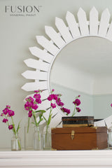 Round mirror with Picket Fence Fusion Mineral Paint sunburst frame, pink flowers in jars, and wooden box.