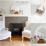 Fireplace painted in Picket Fence Fusion Mineral Paint, with a sunburst mirror, flowers, and striped chairs.