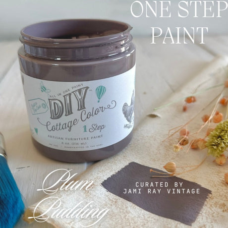 Open jar of DIY Paint Co. Plum Pudding Cottage Color with matching paint swatch and dried flowers nearby.