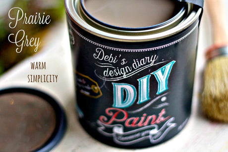 Open can of DIY Paint Co. Prairie Gray with paintbrush poised for use.
