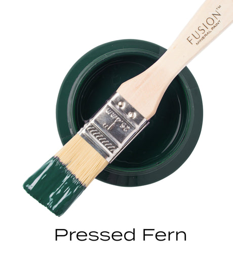 Brush resting on open Fusion Mineral Paint jar in Pressed Fern, a dark green shade.