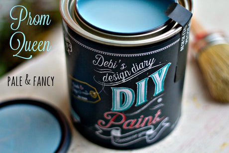 Can of Prom Queen DIY Paint by DIY Paint Co., pale blue, with brush and lid resting alongside.