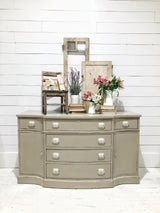 Beige dresser painted with Proper by Sweet Pickins Milk Paint, white handles, topped with flowers and books.