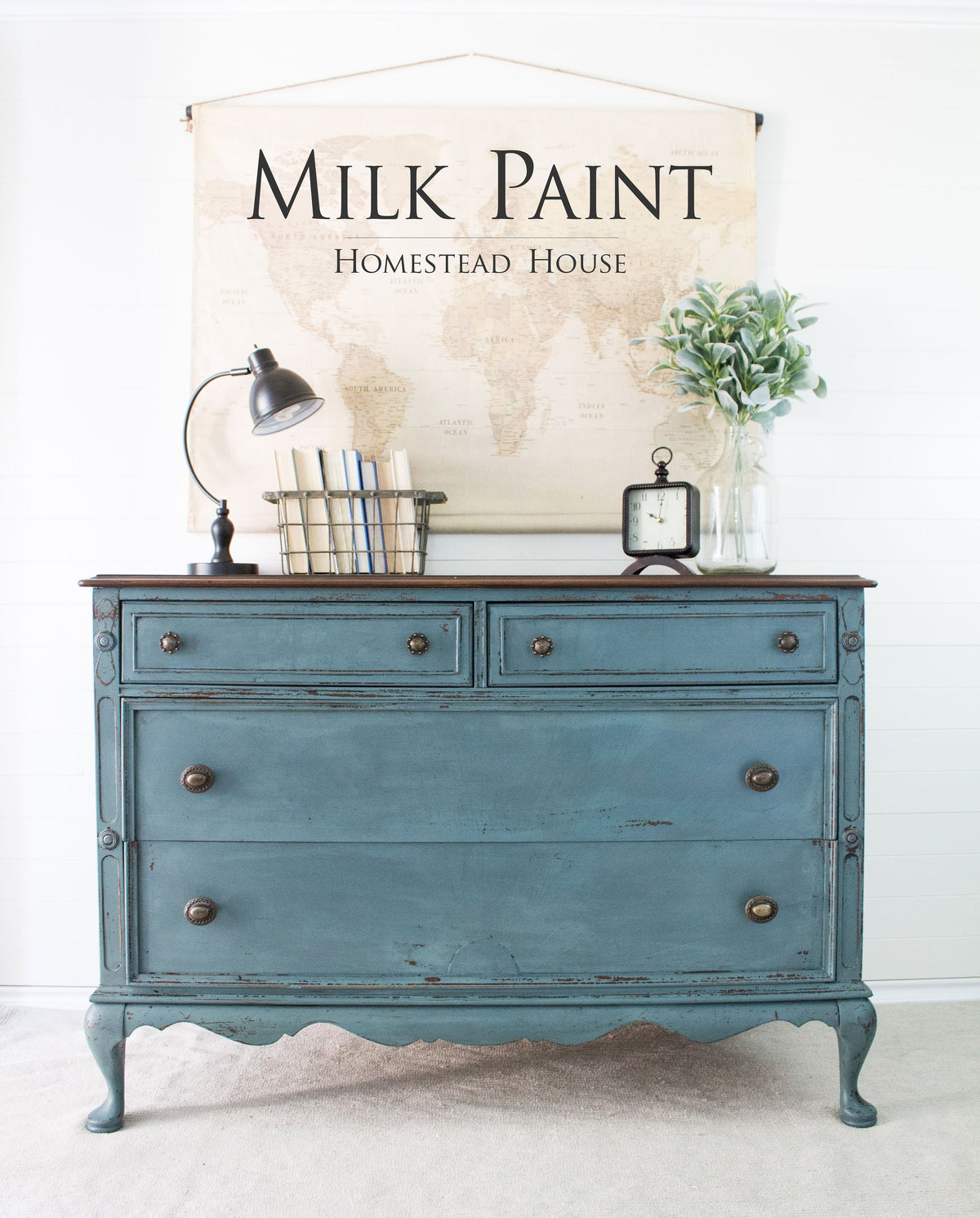 Blue vintage dresser painted in Quaker Blue Milk Paint by Homestead House, displayed with branded signage behind.