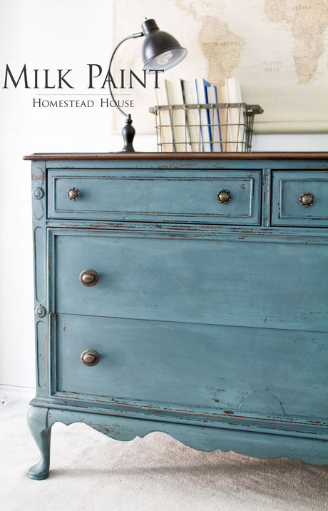Dresser painted in Homestead House Quaker Blue Milk Paint, styled with books and a lamp.