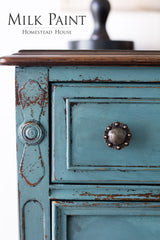 Distressed blue drawer with knob, labeled “Quaker Blue Milk Paint by Homestead House”.