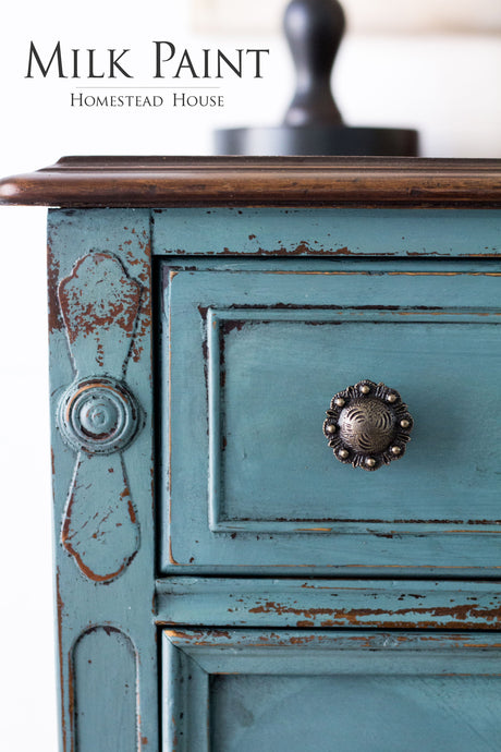 Distressed blue drawer with knob, labeled “Quaker Blue Milk Paint by Homestead House”.