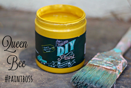 Open jar of Queen Bee DIY Paint by DIY Paint Co. next to a brush with dried bristles.