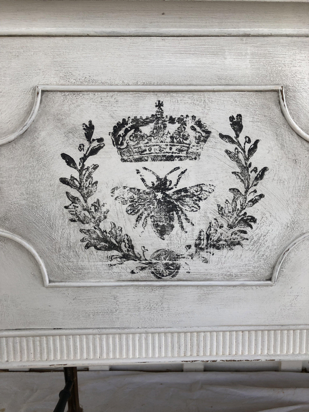 Black crown, laurel, and bee design from Queen Bee Stamp by IOD on distressed white wood background.